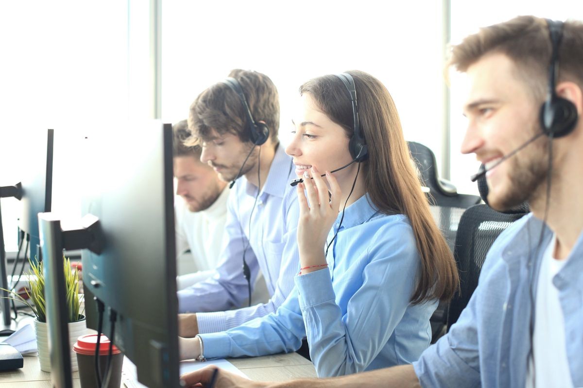 Portrait of call center worker accompanied by her team. Smiling customer support operator at work